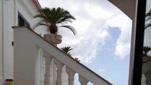 Una escalera con barandillas blancas que lleva a un balcón con vista al mar.
