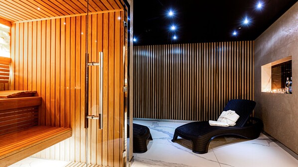 A sauna room with wooden slats, a massage chair, and a small bar area. - Grand City Hotel Wrocław (Wroclaw)