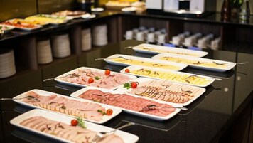 Un bufé con diversas opciones de comida, como carnes cortadas y ensaladas.