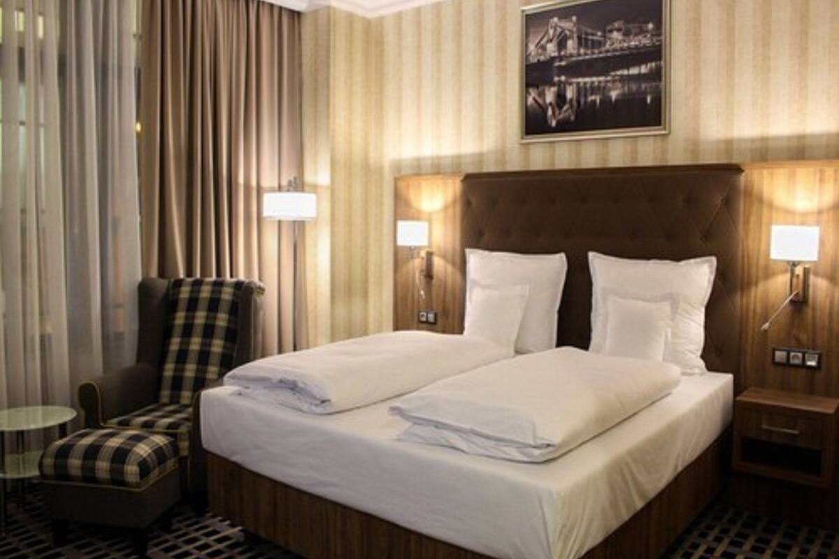 A hotel room with a large bed, two bedside tables, a chair, and a view of a bridge.