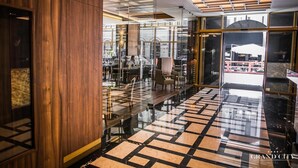 A modern hotel lobby with a glass partition, wooden paneling, and a patterned floor. - Grand City Hotel Wrocław (Wroclaw)