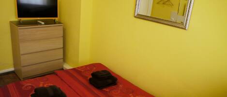 A room with a bed, a dresser, a television, and a mirror.