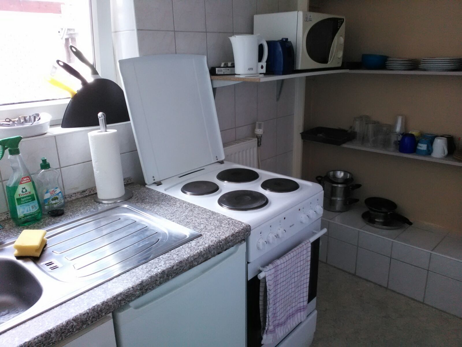 A kitchen with a stove, sink, and various kitchen utensils.