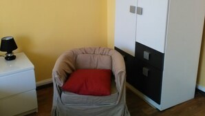 A room with a chair, a small bedside table with a lamp, and a wardrobe. - SleepInHamburg St.Pauli Apartment 35&36 (Hamburg)
