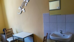 A small bathroom with a sink, mirror, and a decorative lizard wall piece. There are two chairs and a table. - SleepInHamburg St.Pauli Apartment 35&36 (Hamburg)