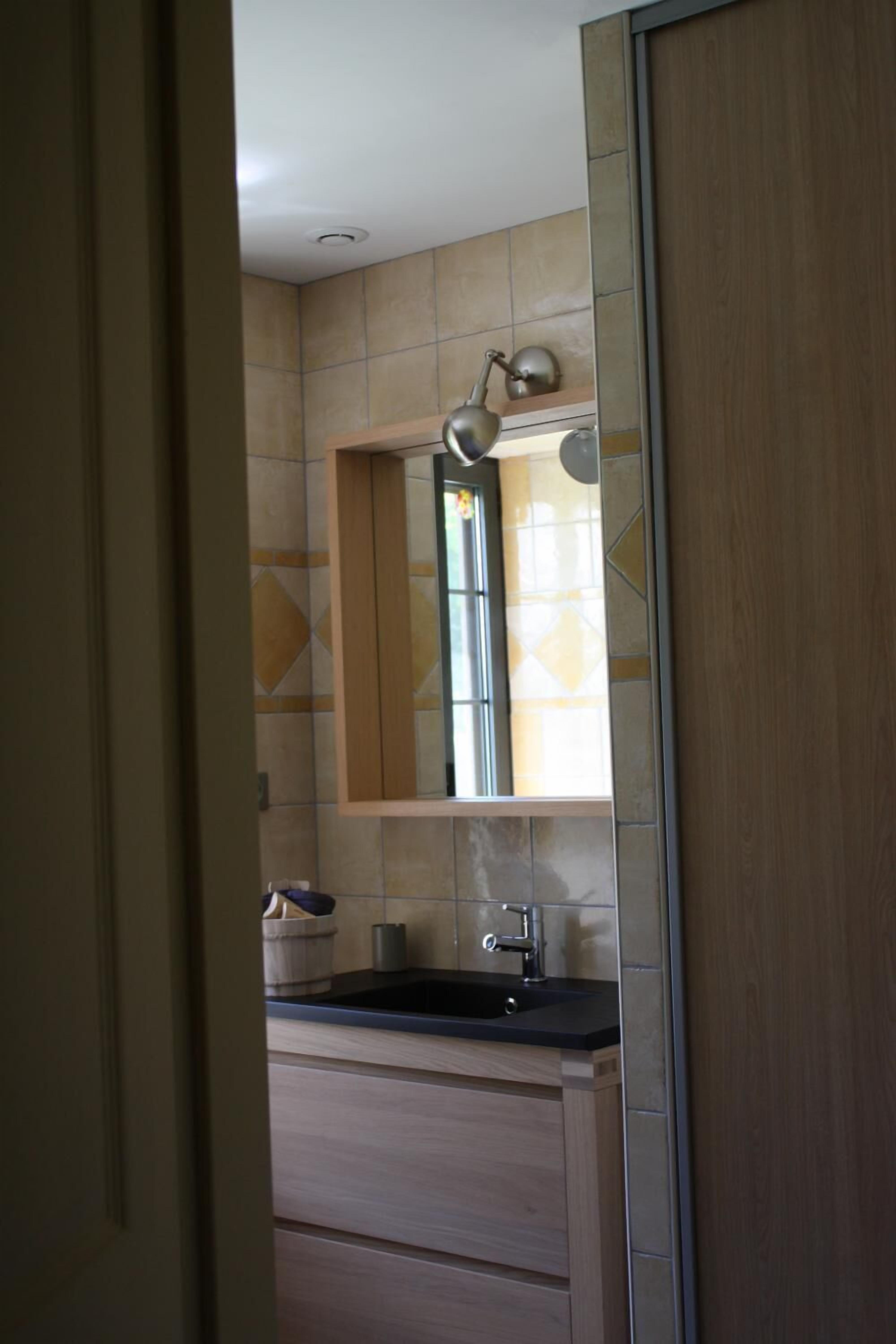 Un bagno con lavandino, specchio e mobiletti.