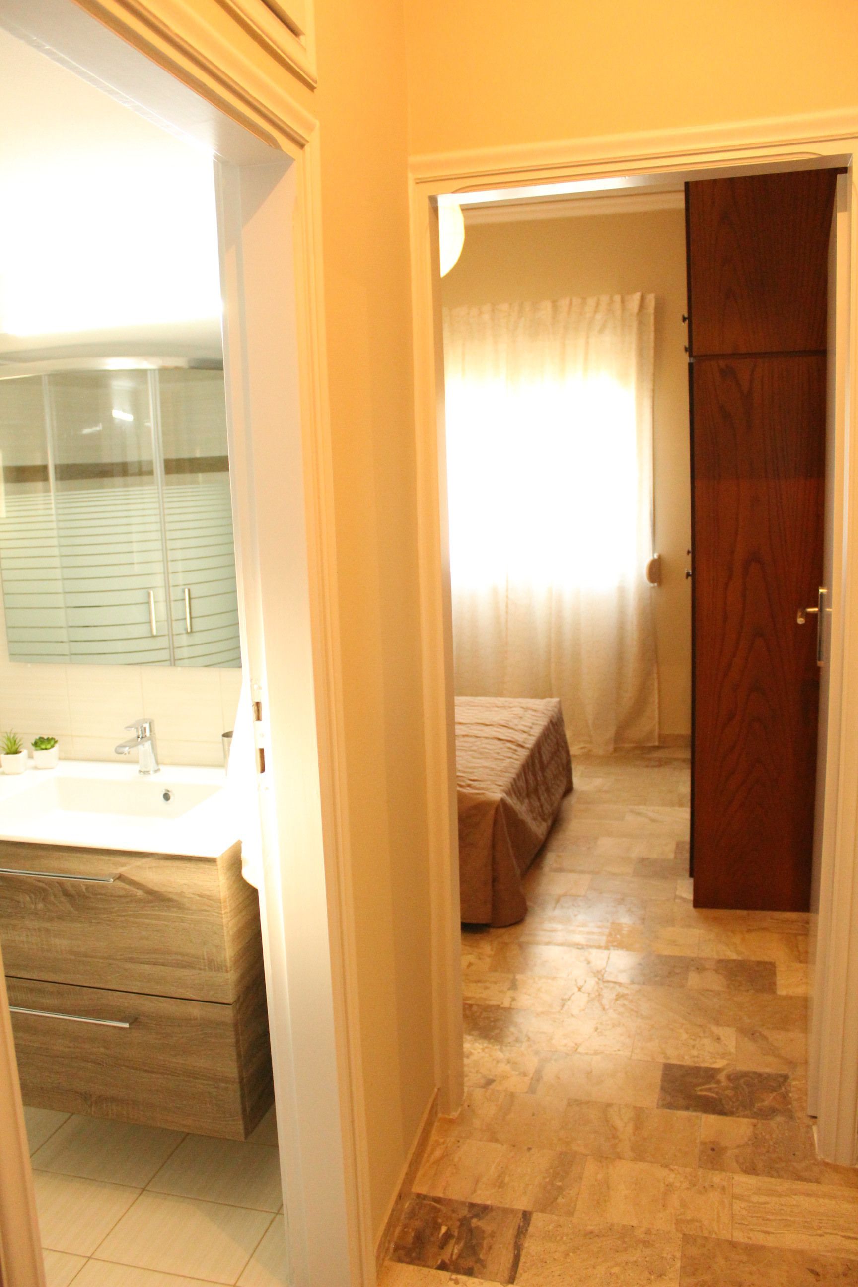 A bathroom with a sink, mirror, and wooden cabinet.