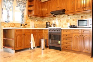 A kitchen with wooden cabinets, a stainless steel oven, a microwave, and a coffee maker. - The House of Travelers (Spata-Artemida)