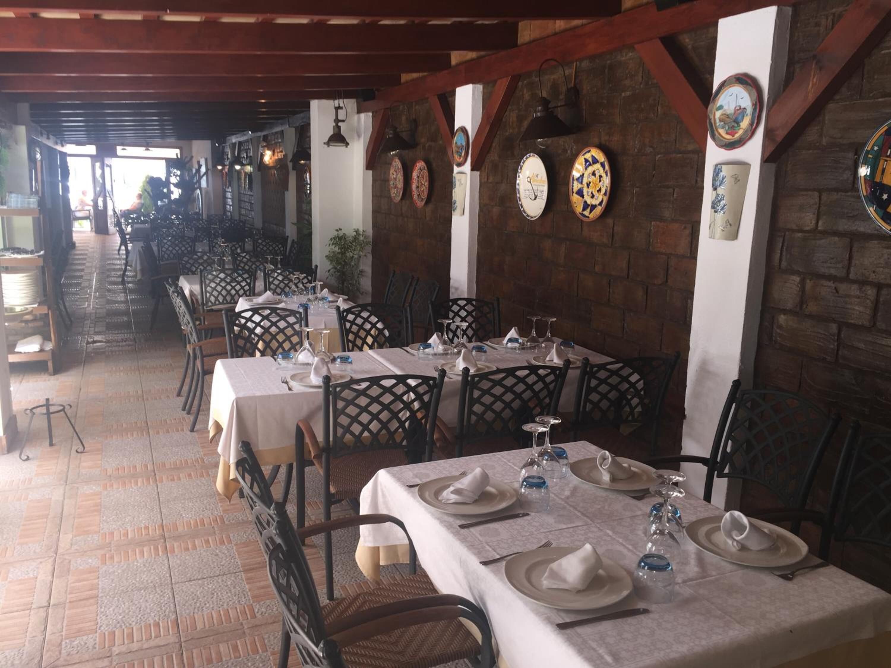 Un restaurante con varias mesas dispuestas para comer, que presenta una pared de ladrillo y vigas de madera.