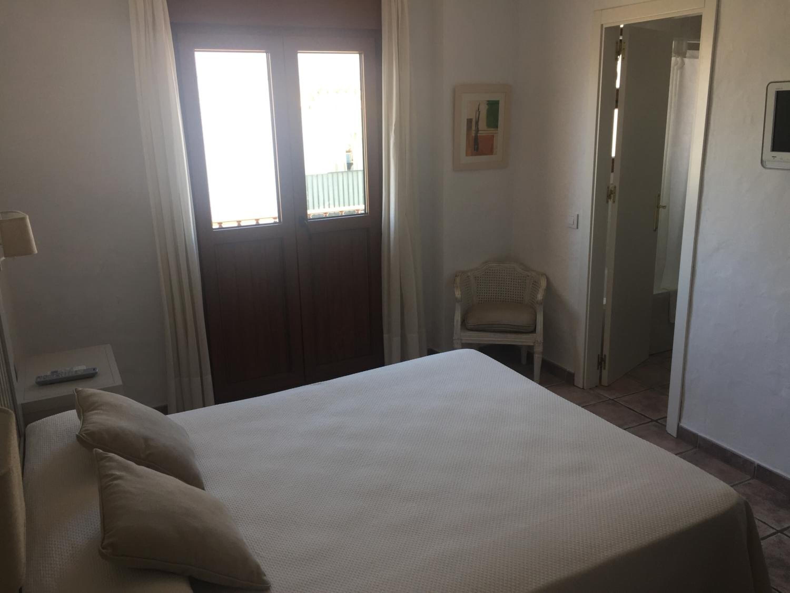 Une chambre à coucher avec un lit, une chaise, une porte et une fenêtre.
