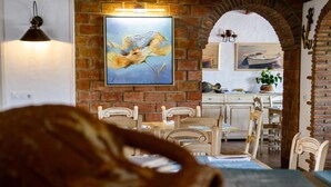A dining area with a brick wall, wooden chairs, and a table. - Hotel Almadraba (Barbate)