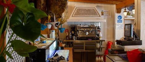 A restaurant interior with hanging roasted chickens, a bar area, and a kitchen.