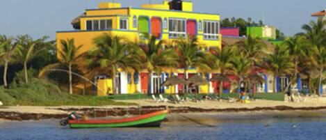 A colorful building with multiple stories, surrounded by palm trees and a beach.