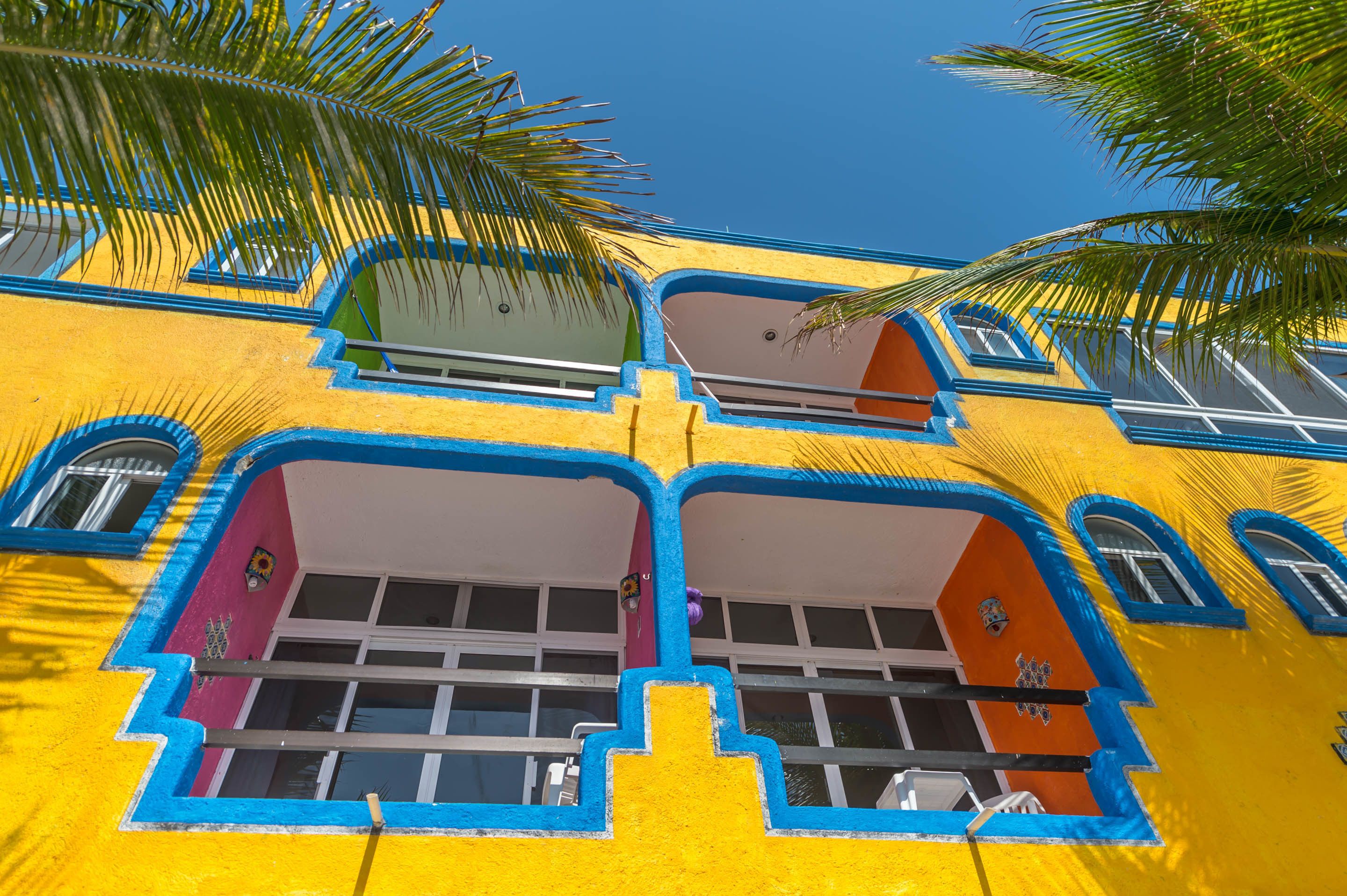Un edificio de colores vivos con varios balcones y ventanas, que presenta un estilo arquitectónico distintivo con detalles azules y amarillos.