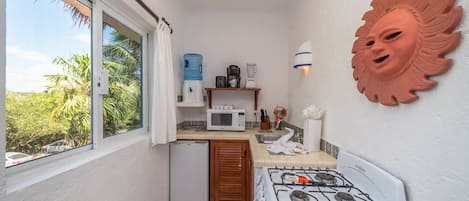 A compact kitchen with a gas stove, microwave, and small refrigerator.