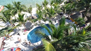 Um resort à beira-mar com piscina, palmeiras e espreguiçadeiras.