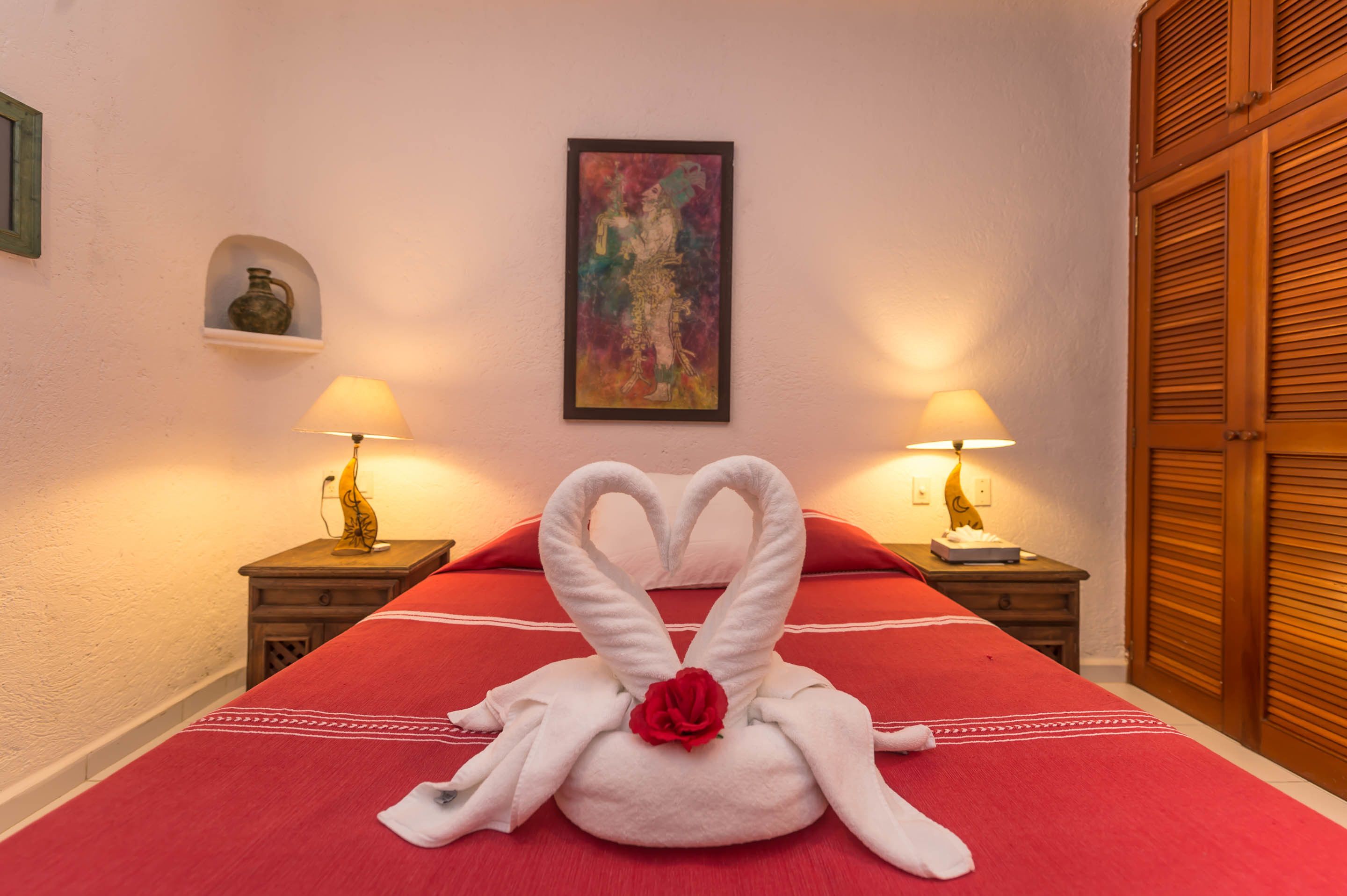 A hotel room with a bed, two nightstands, a painting on the wall, and a wooden door.