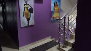 A staircase with metal railings leading to a landing with two wall-mounted paintings. - De Love Hotel (Lagos)