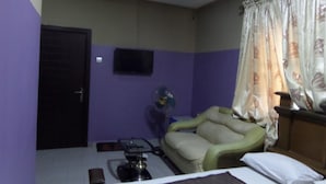 A room with a bed, a sofa, a television mounted on the wall, and a door. - De Love Hotel (Lagos)