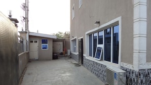 A narrow alleyway with a building on one side featuring a large window and a door. - De Love Hotel (Lagos)