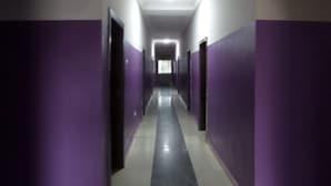 A long, narrow hallway with purple walls and doors on both sides, leading to a bright room at the end. - De Love Hotel (Lagos)