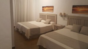 Una habitación de hotel con dos camas, una mesita de noche y lámparas fijadas a la pared.
