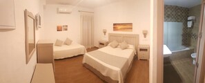 A hotel room with two beds, a bathroom with a bathtub, and a shower. - Hotel Almadrabeta (Barbate)