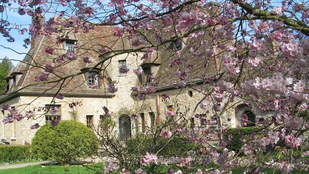 Un edificio in pietra con finestre ad arco e un giardino curato.