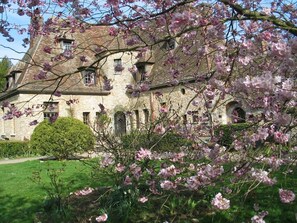 A stone building with arched windows and a well-maintained garden. - Le Logis D'arniere (Saint-Cyr-sous-Dourdan)