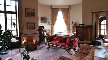 A traditional living room with a patterned rug, a red sofa, and a wooden cabinet.