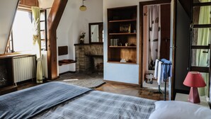 Una camera da letto con un letto, una cassettiera, uno specchio, un camino e una finestra con tende.