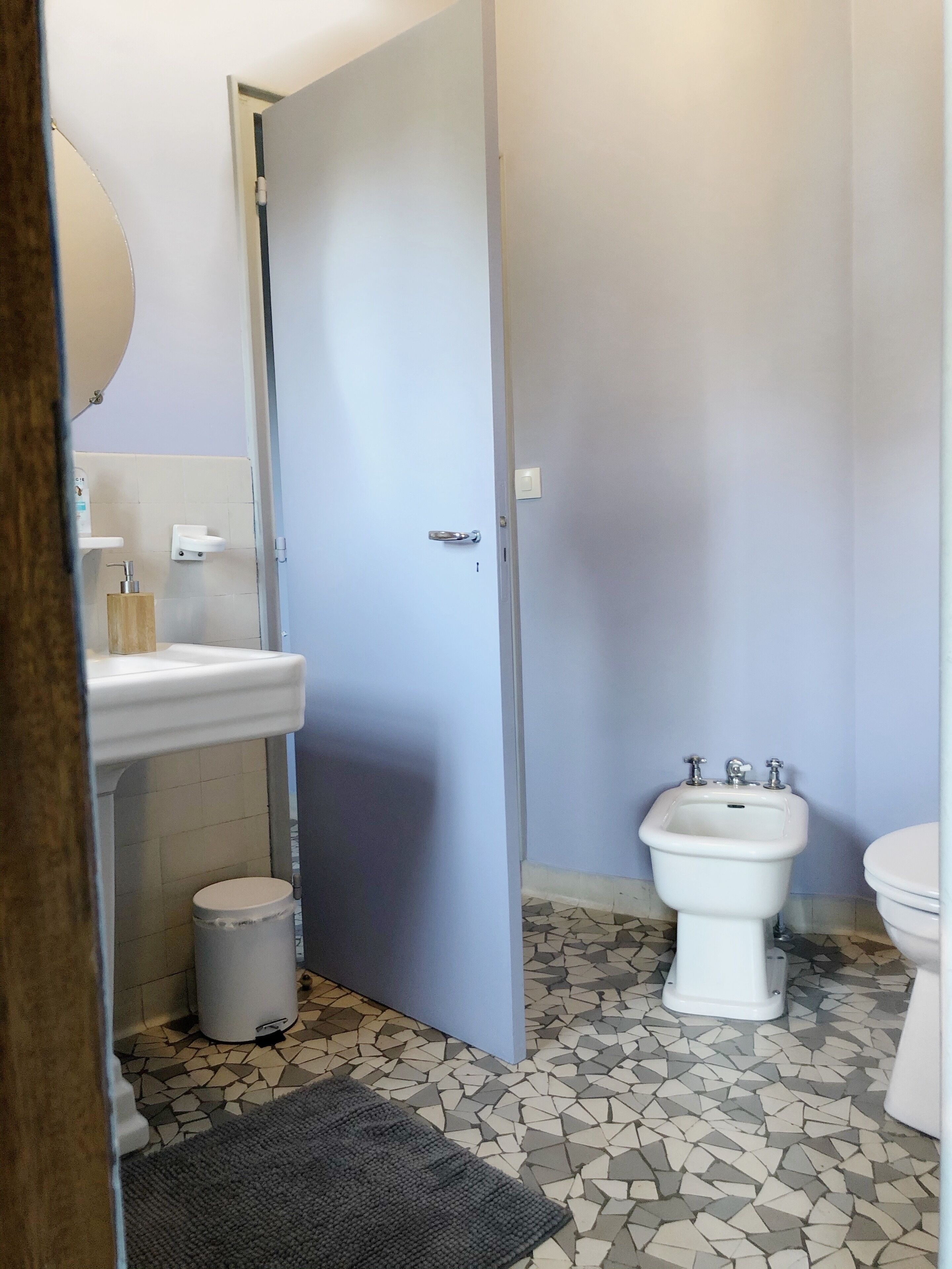 A bathroom with a white sink, a bidet, a toilet, and a tiled floor.