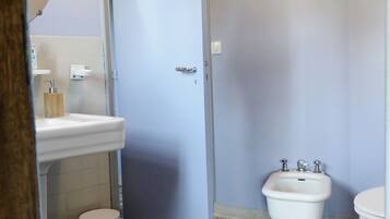 A bathroom with a white sink, a bidet, a toilet, and a tiled floor.