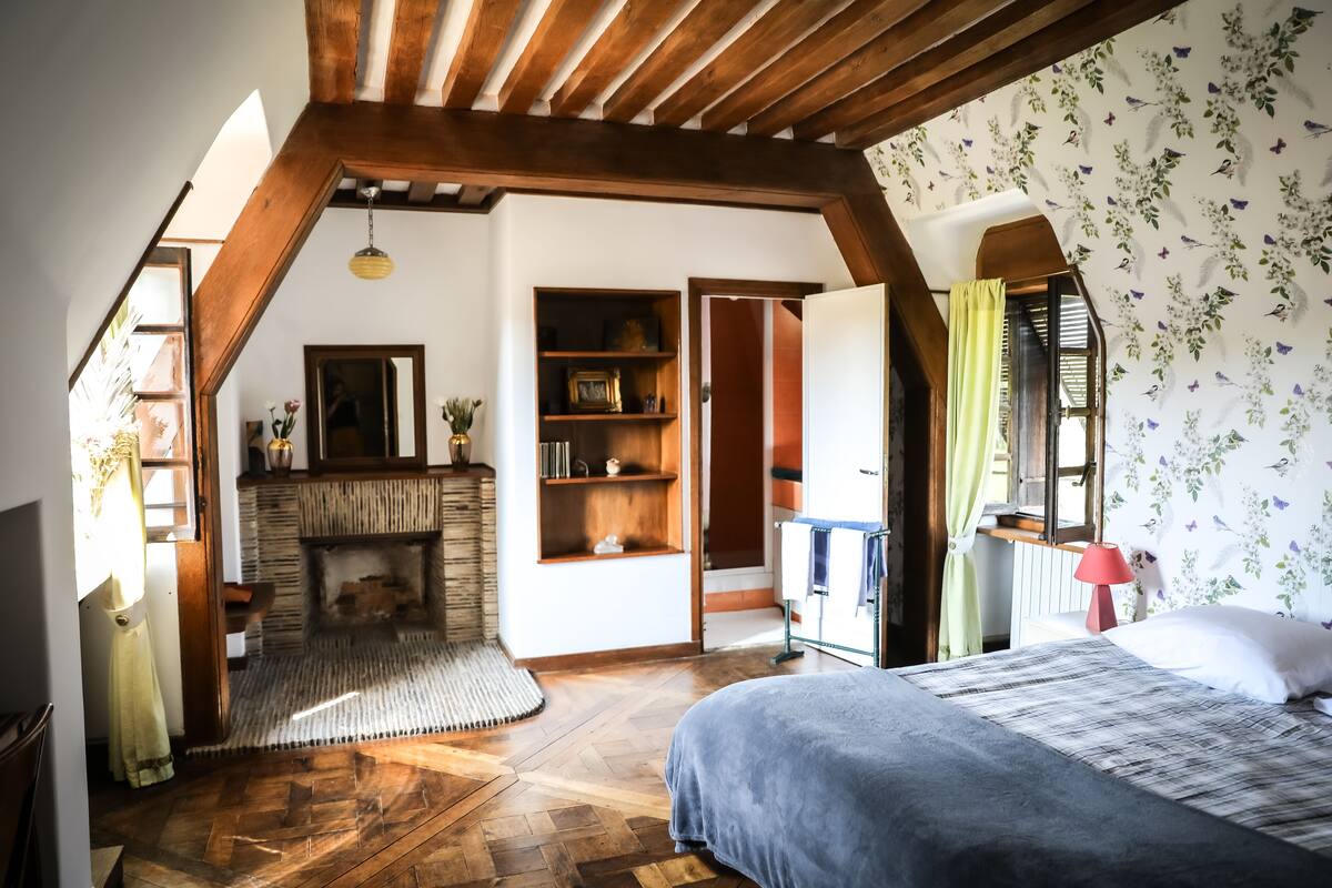 Ein Schlafzimmer mit Holzboden, Kamin, Bett und Kleiderschrank.