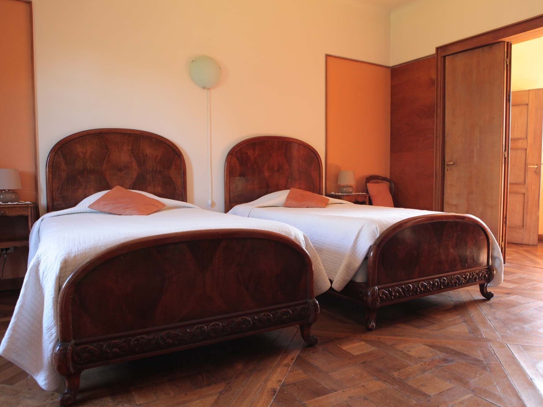 Una habitación con dos camas de madera, un armario y una lámpara.