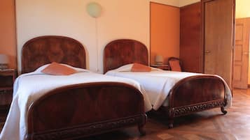 A room with two wooden beds, a wardrobe, and a lamp.