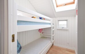 Cozy retreat with a bunk bed, skylight, and window offering a view of the outdoors.
