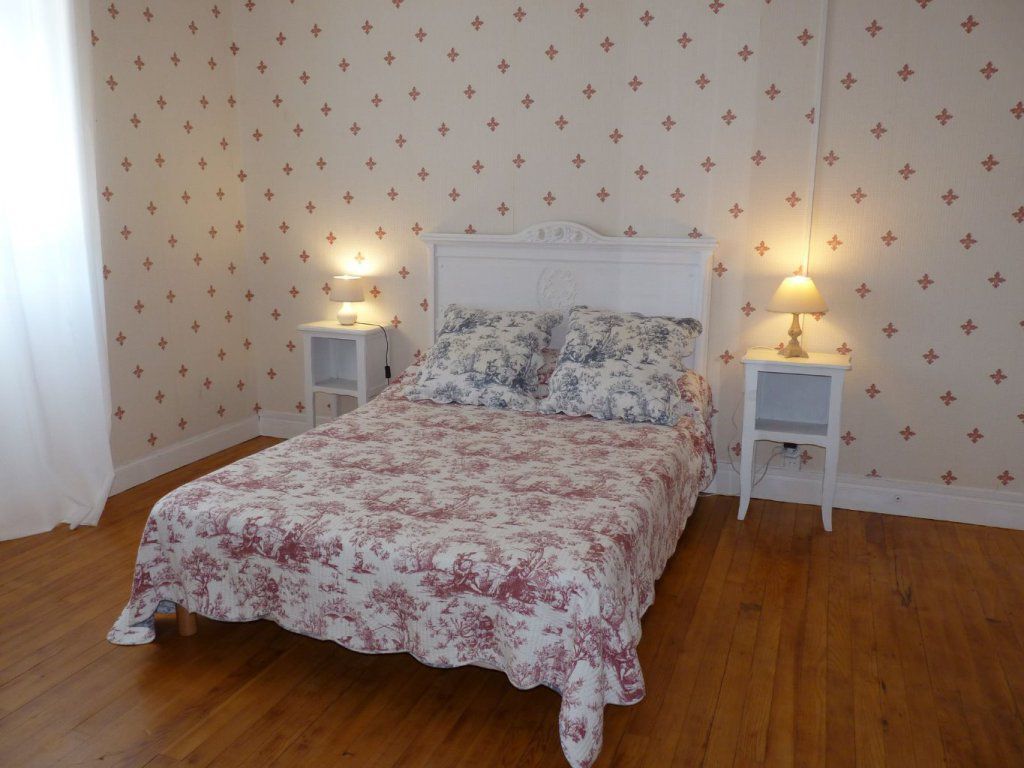 Un dormitorio con colcha estampada de flores, dos mesitas de noche con lámparas y un papel tapiz decorado.