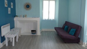 Una habitación con pared azul, banco blanco, sofá púrpura y ventana con cortinas blancas.