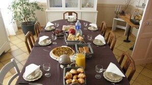 Una mesa de desayuno dispuesta con cruasanes, tarta y jugo de naranja.
