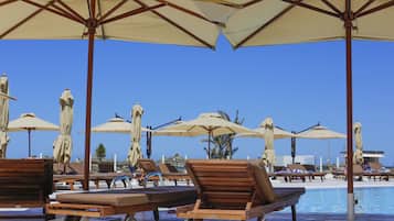 Una piscina techada, una piscina al aire libre, sombrillas