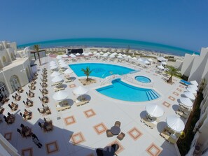 A resort pool area with multiple sun loungers and umbrellas, a central pool, and a view of the beach. - Hotel  Telemaque Beach & Spa  - Families and Couples Only (Mezraia)