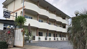 Un hotel de varios pisos con un diseño de balcón curvo, fachada de piedra y entrada con portón.