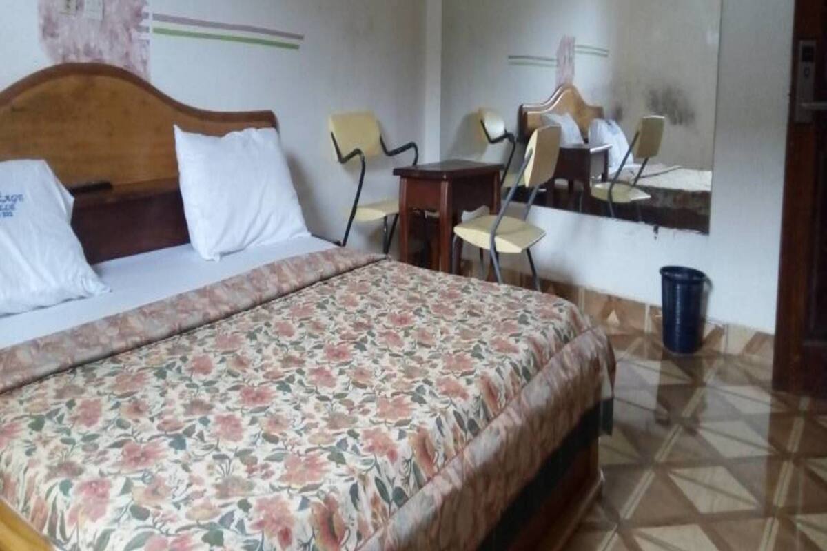 A hotel room with a bed, a desk, and a chair.