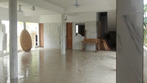 A spacious, unfinished interior with marble flooring, large pillars, and a central wooden table. - Complexe Hôtelier Paris Village (Abidjan)