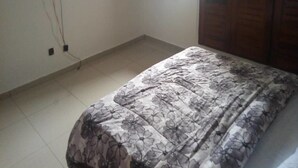 A bedroom with a bed, a television mounted on the wall, and a window with curtains. - Complexe Hôtelier Paris Village (Abidjan)