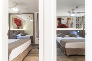A hotel room with a bed, a ceiling fan, a mirror, and artwork on the wall. - Parque de las Americas (Adeje)