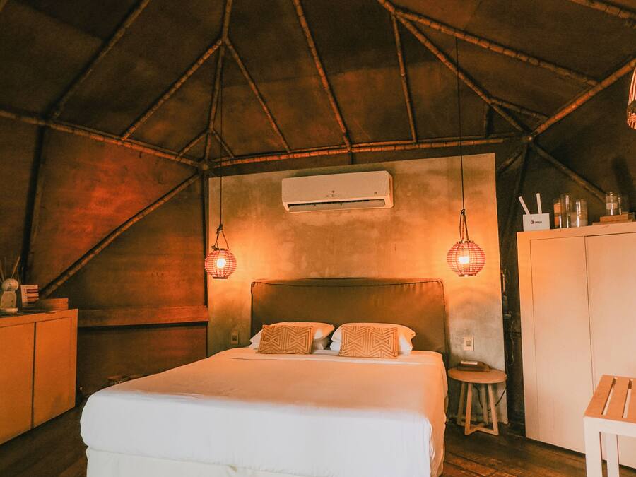 A cozy, dimly lit room with a large bed, a wooden floor, and a patterned rug.