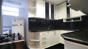 Une cuisine de taille réduite avec des meubles blancs, un plan de travail noir et une cuisinière intégrée.