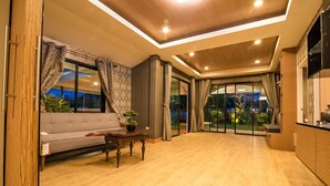 A modern living room with a sofa, a coffee table, and a view of the outdoors. - GetZleep House Sattahip (Sattahip)
